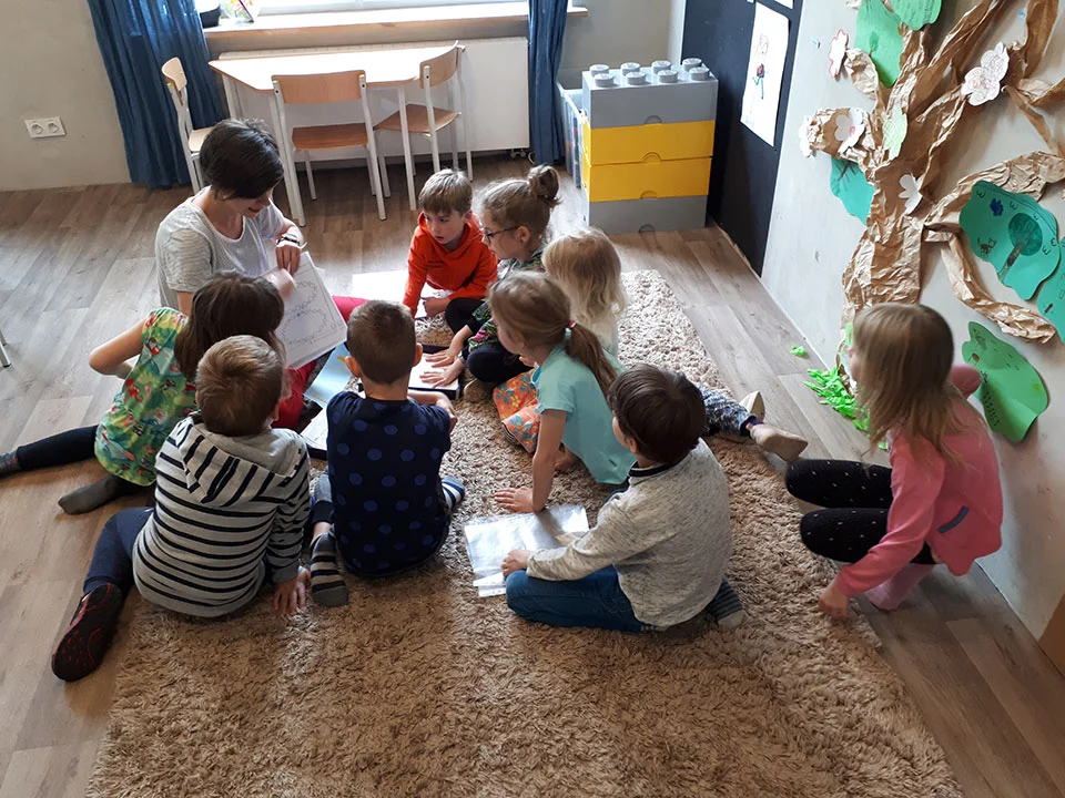 Nauczycielka pracuje z małą grupą dzieci w kręgu na dywanie